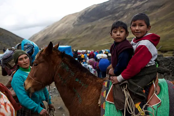 two kids and a woman saying a Guide to attend Qoyllur Rit’i as a tourist