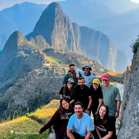 Trekkers celebrating their achievement at Machu Picchu after completing the Salkantay Trek, with the iconic ruins and majestic mountains in the background.
