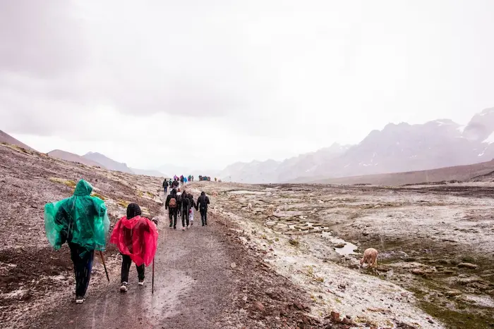 People trekking while wearing protective layers for the rainy season, a sign of summer in Peru.